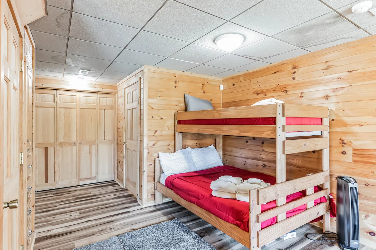 A bunk bed arrangement with soft bedding, wooden walls, and a cozy rug. The space feels playful yet comfortable, evoking memories of sleepovers, late-night laughter, and creating new traditions with friends or family.