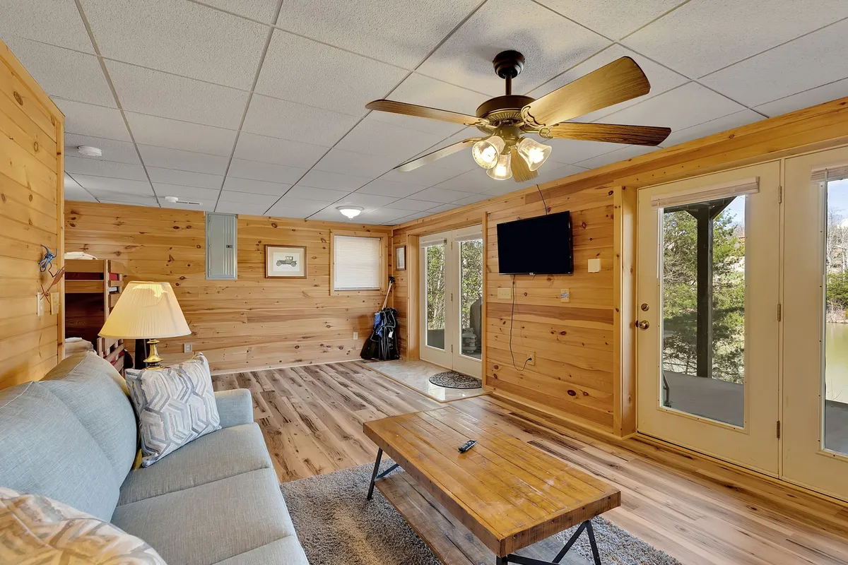 A cozy living room featuring a comfortable sofa, a coffee table, and double doors that lead outside. Warm natural light suggests a connection to the outdoors, and the arrangement encourages intimate relaxation or conversation, with a view of the surrounding landscape visible through the doors.
